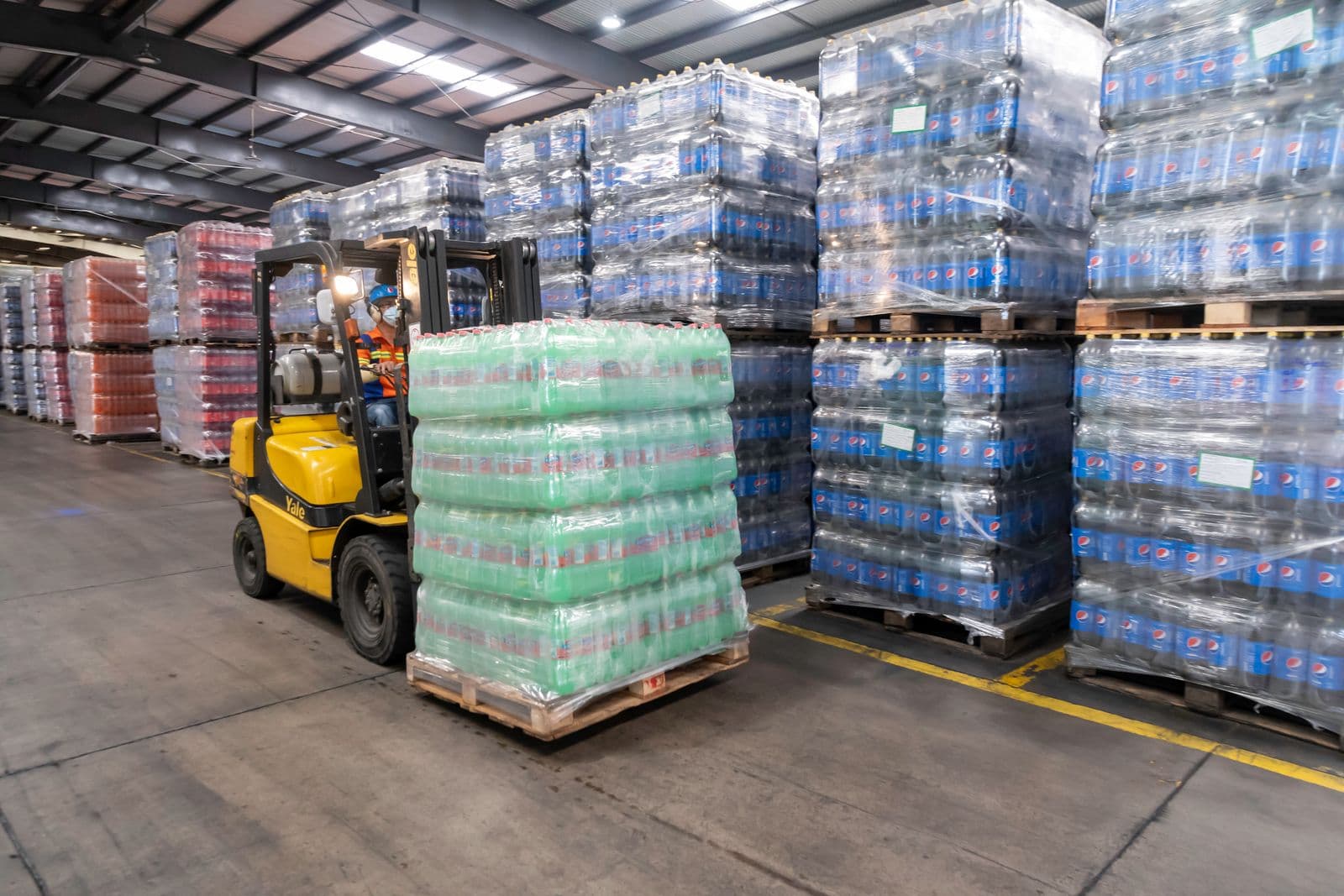 Forklift operating in a busy warehouse aisle