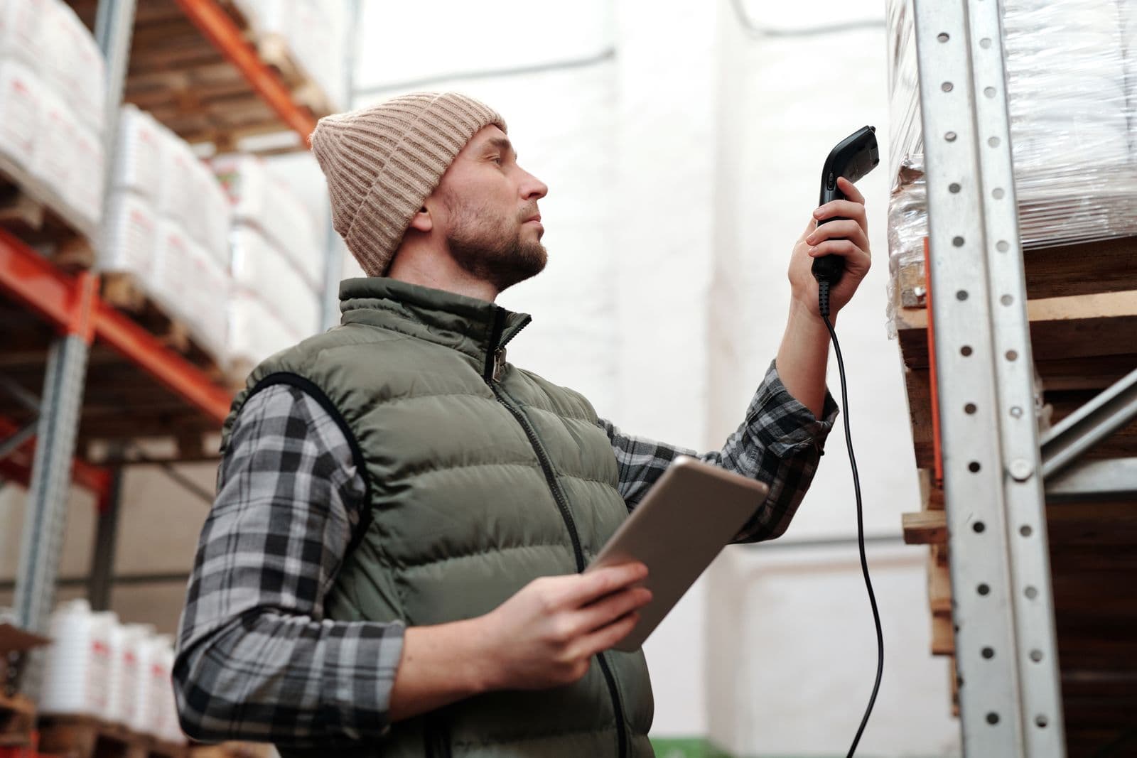 Warehouse worker scanning inventory with a handheld scanner and tablet